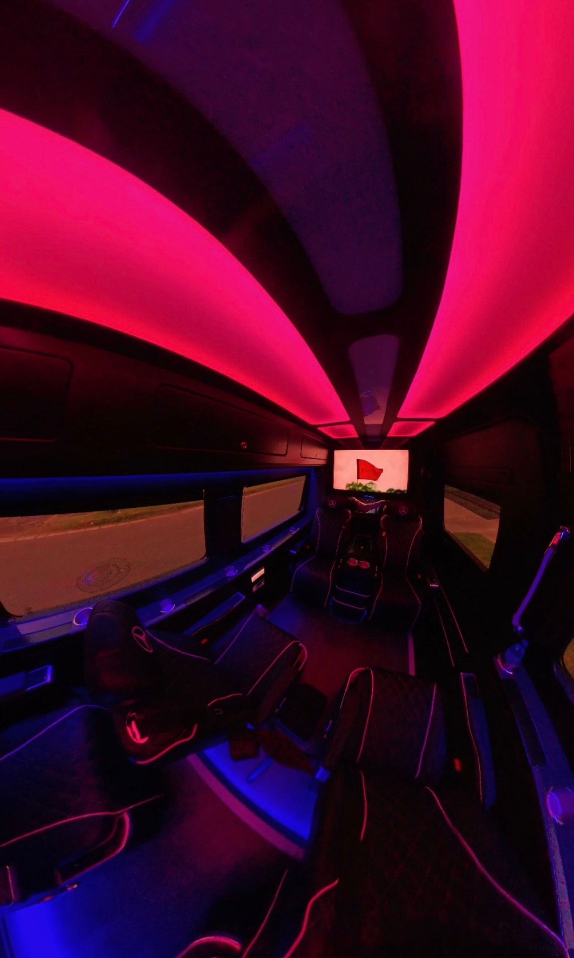 Sprinter cabin bathed in red ambient lighting with a screen at the front