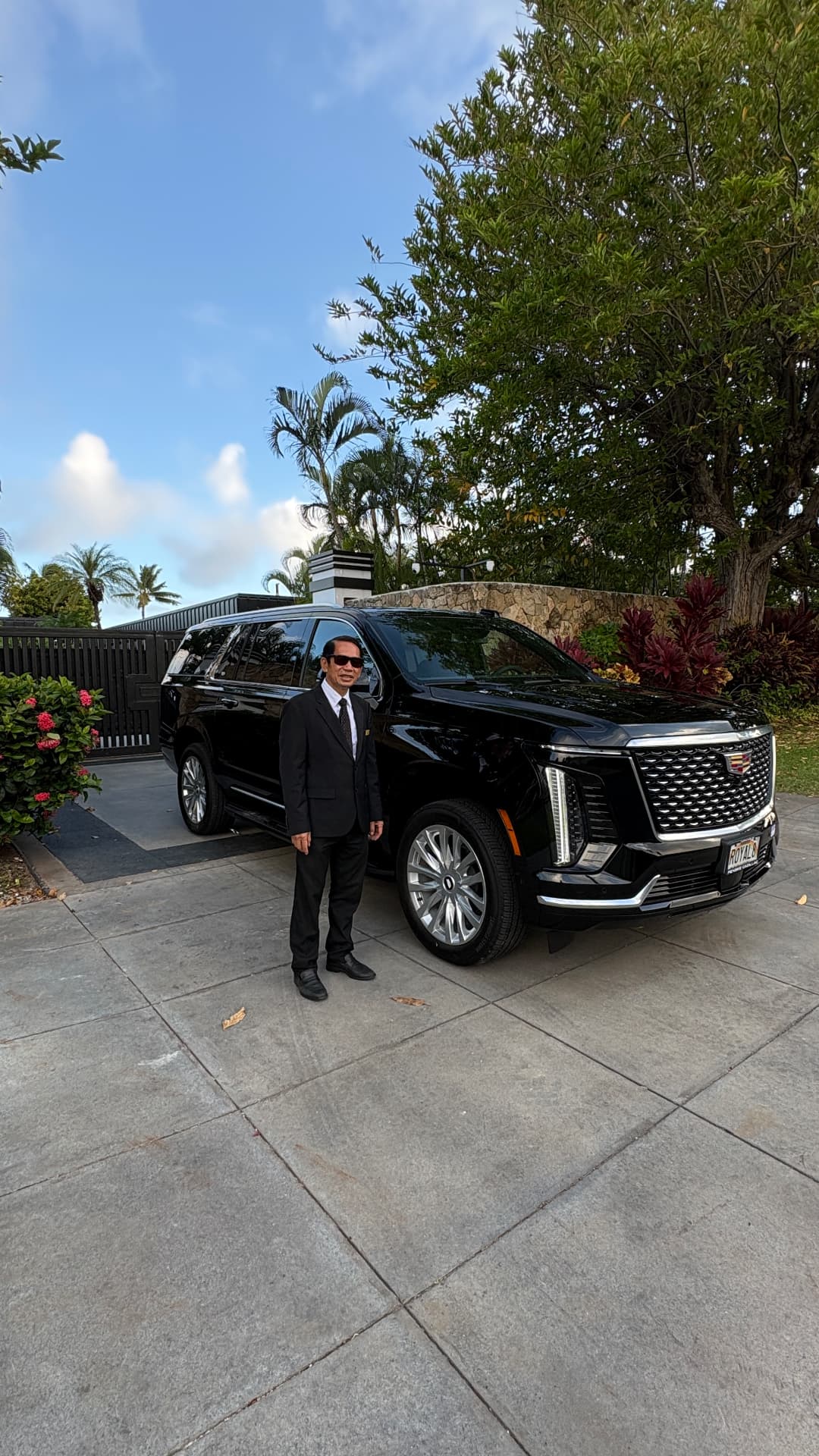 AURA chauffeur beside black Escalade